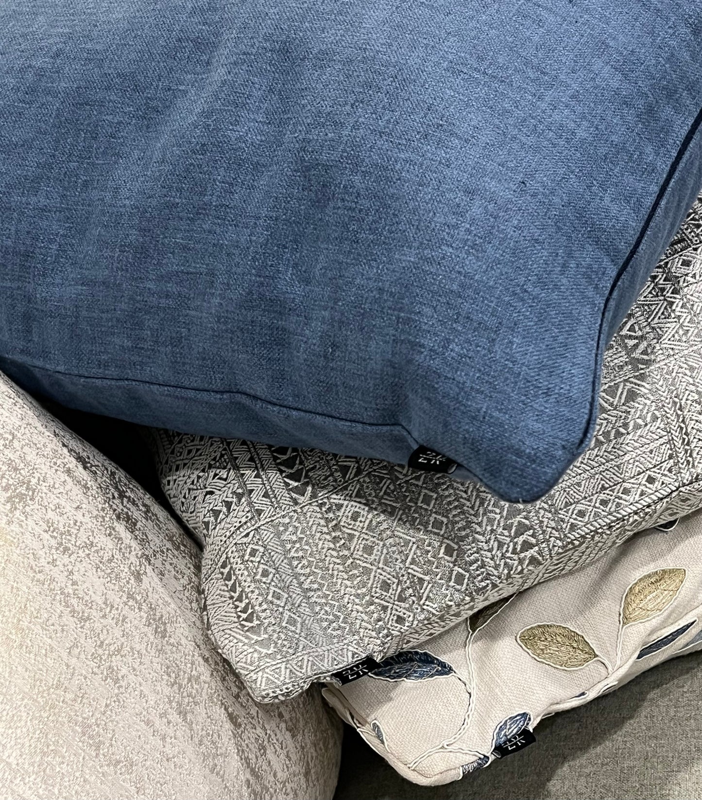 close up shot of ink blue cushion stacked on other cushions 