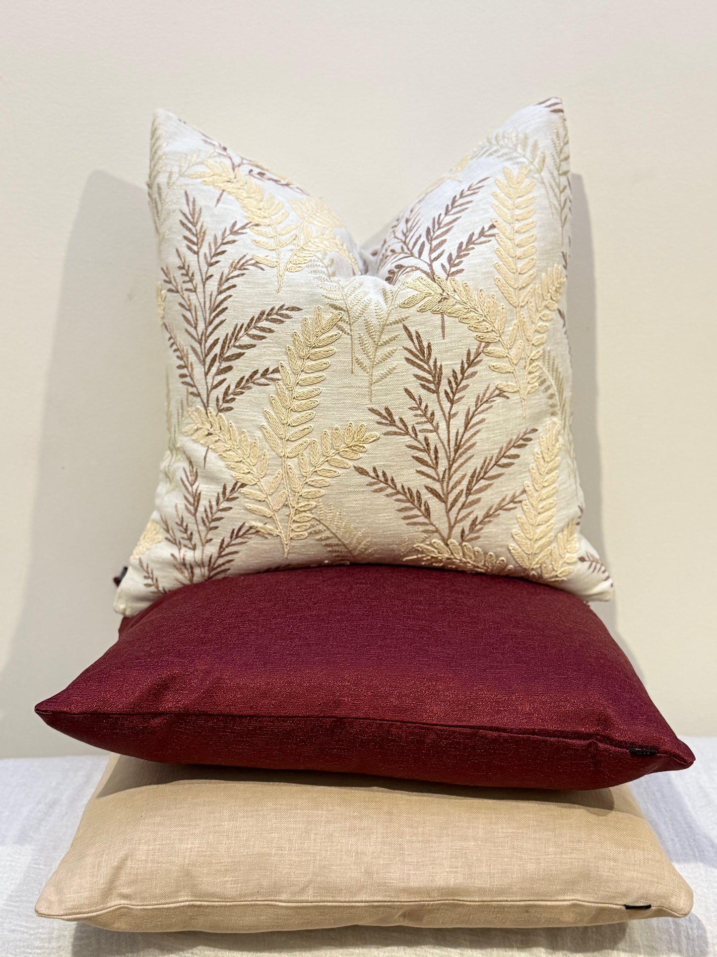 Ruby Luxe Cushion styled with neutral cushions on a beige sofa for bold contrast
